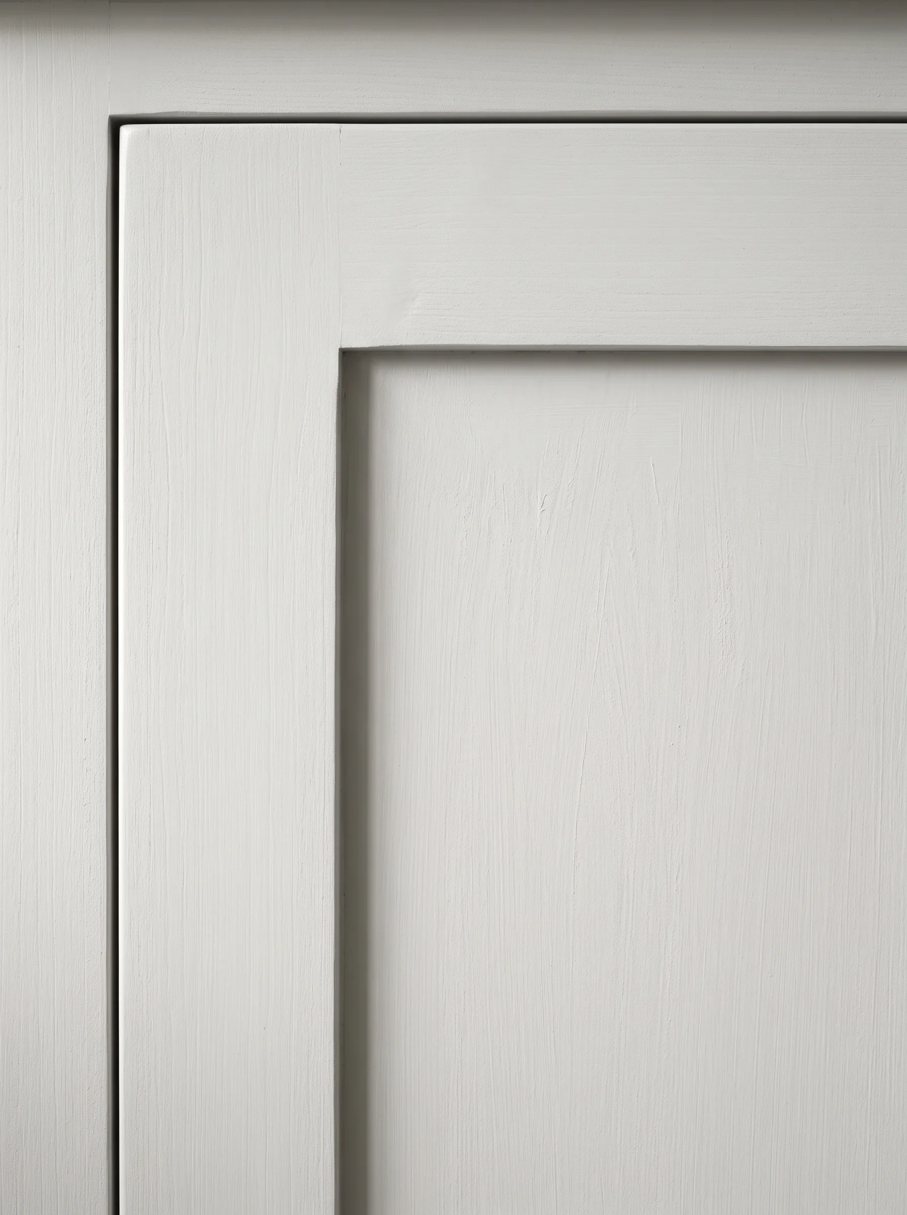 A limewash-painted shaker door in raking light, the frame and recessed panel casting a soft shadow that shows their depth